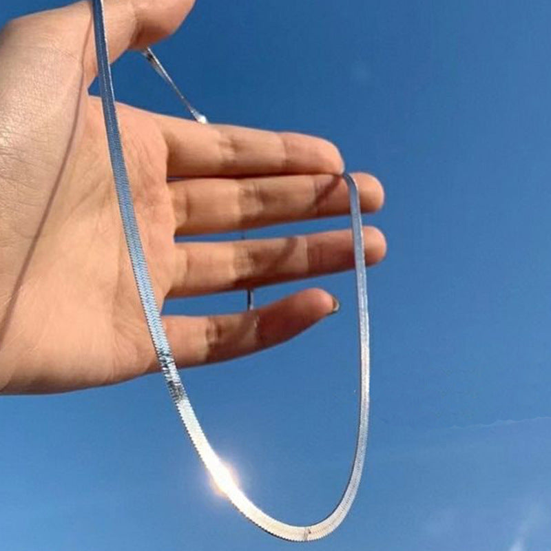 Close-up: Sleek gold snake chain necklace for women. Minimalist fashion jewelry, perfect for elegant styling.