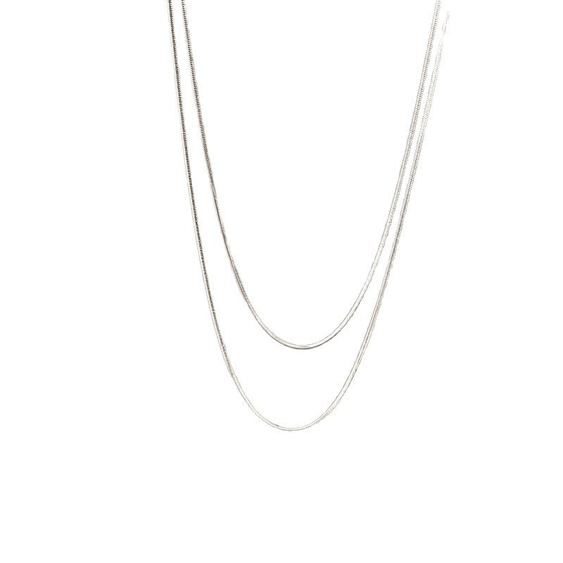 Close-up of a women's layered chain necklace, sleek gold and silver tones, ideal elegant gift for her.