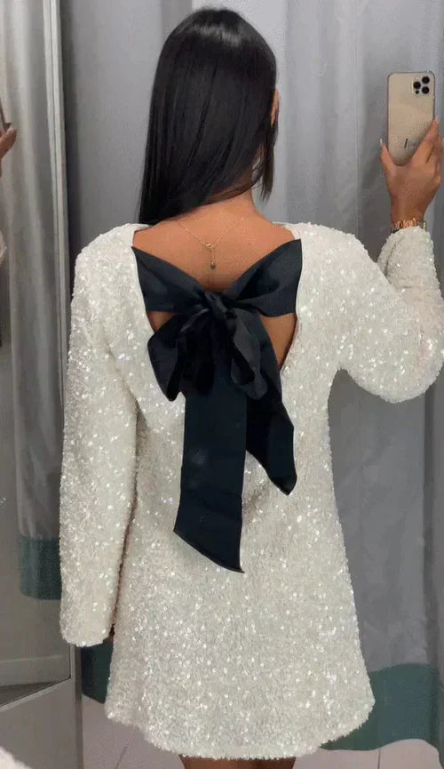 Black cocktail dress with a dazzling glitter finish and a stylish bow back.