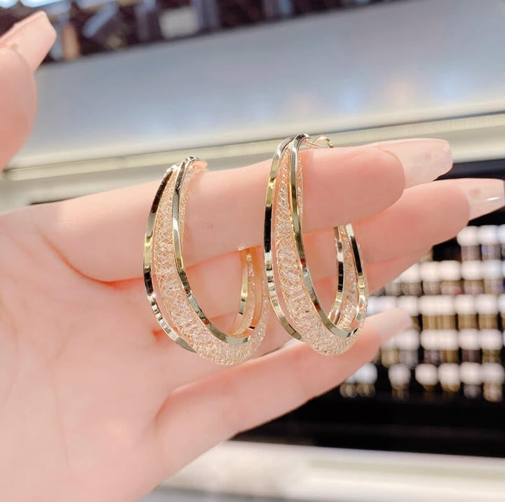 Elegant women's twisted oval hoop earrings, featuring sparkling crystals. Perfect fashion accessory for any outfit.