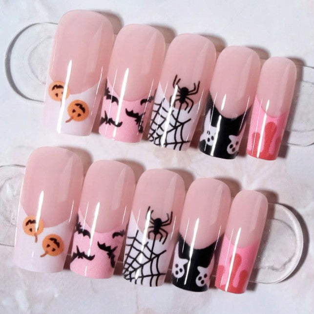 Close-up of women's Halloween press-on nail art: black bats, spiders & webs on glossy nude pink. Easy application.