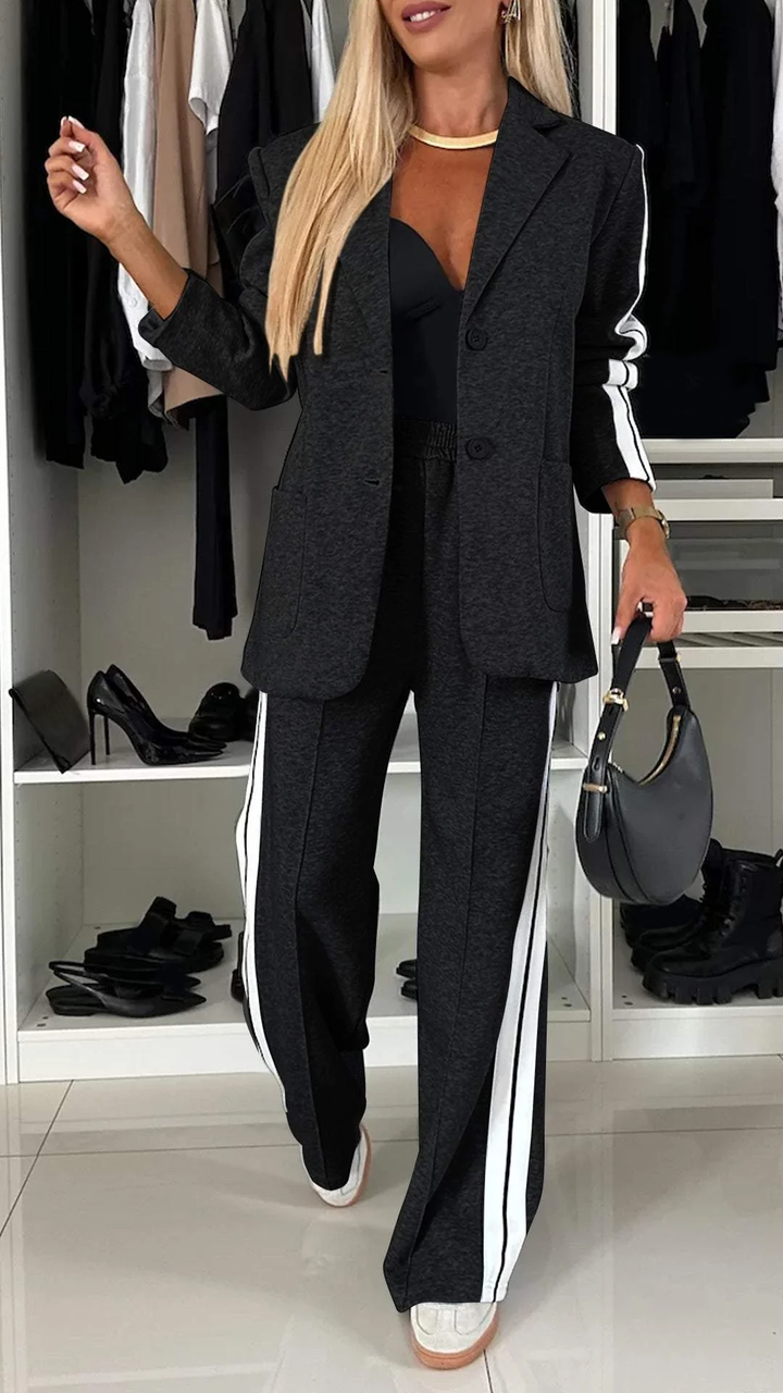 Full view of women's sporty chic suit set. Casual elegant two-piece with oversized blazer & striped pants.