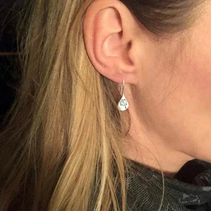 Close-up of women's sterling silver dandelion teardrop earrings, showcasing intricate real dandelion seeds inside.