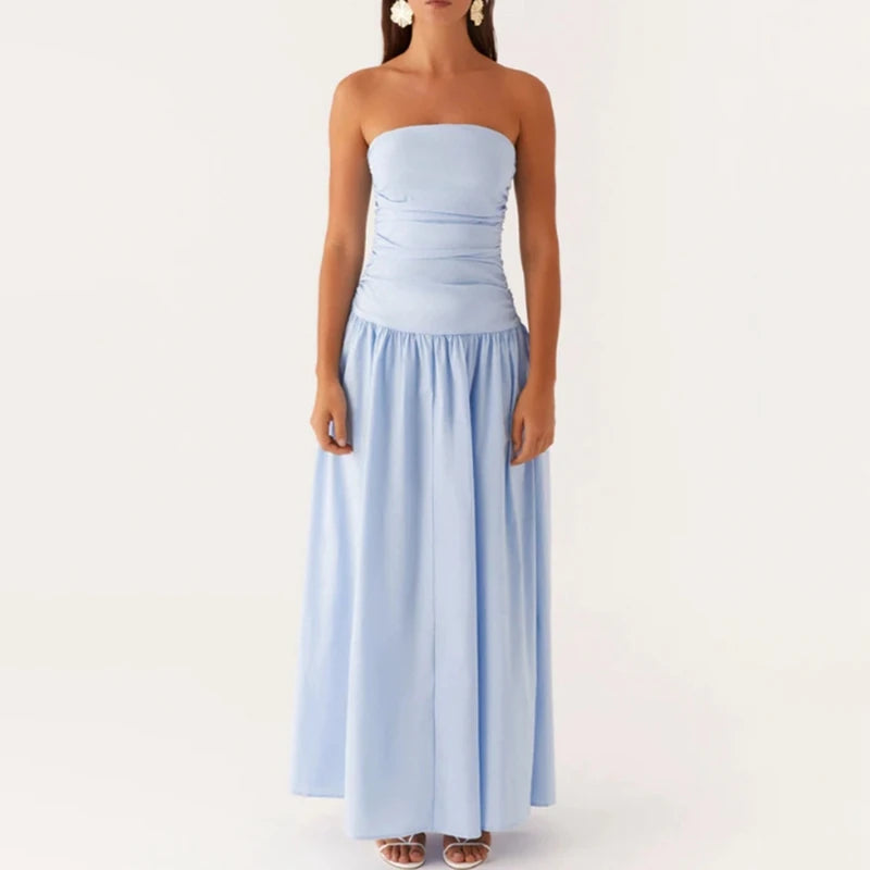 Women's strapless summer maxi dress paired with vacation accessories, flowy and chic style.