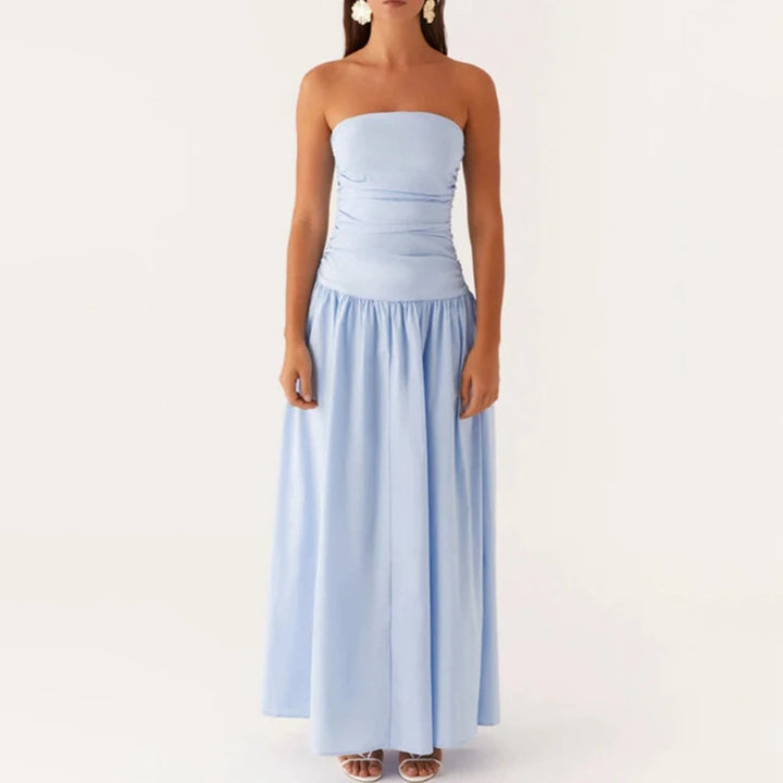 Women's strapless summer maxi dress paired with vacation accessories, flowy and chic style.