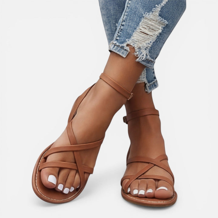 Women's flat strappy sandals with adjustable ankle buckle, designed for comfortable and stylish summer wear.
