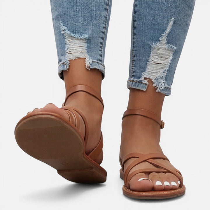 Elegant black strappy flat sandals for women, featuring a secure ankle buckle and comfortable design.