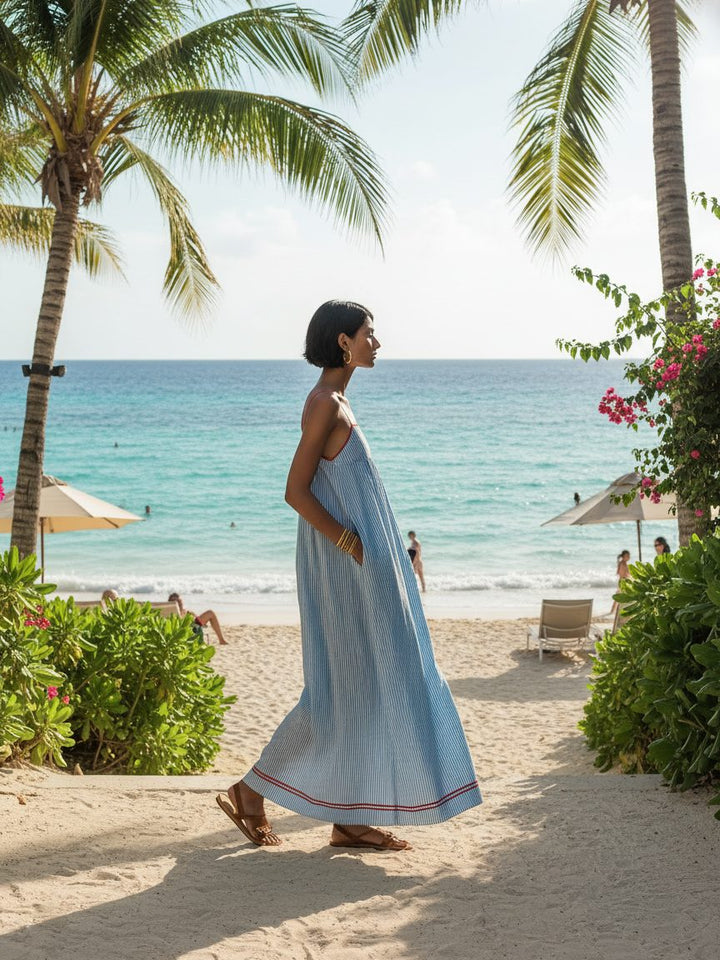 Woman modeling a chic striped maxi dress with pockets, ideal for sunny summer days.