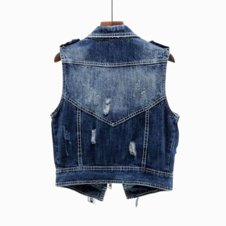 Casual women's distressed denim vest with a moto style, perfect for layering and adding an edgy look.