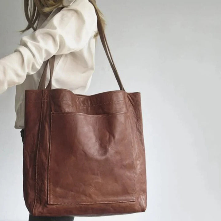 Close-up of a women's stylish PU leather tote bag showing the magnetic snap closure and front pocket detail.