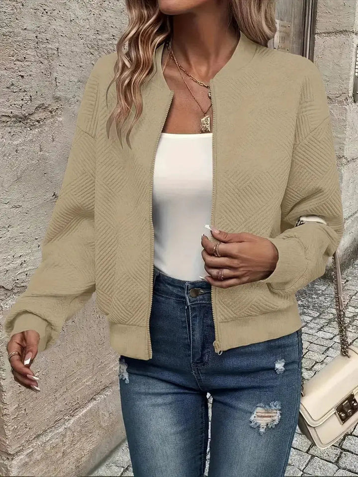 Detail of the zip-up closure on a women's stylish quilted bomber jacket. Cropped, fashion outerwear.