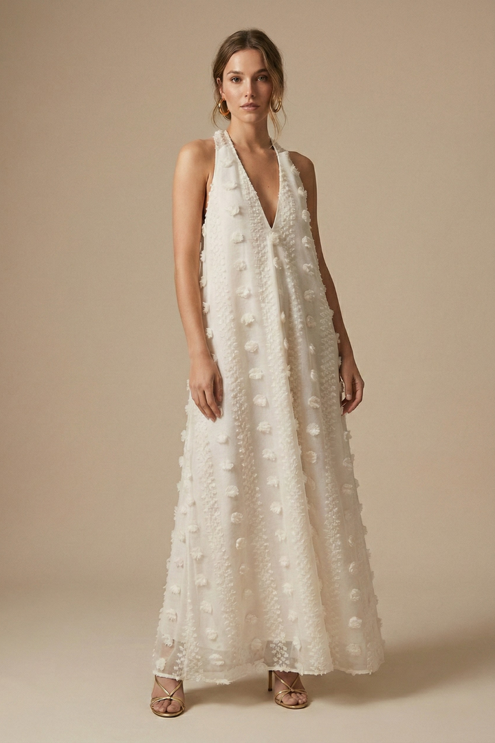 Women's textured halter backless maxi dress with delicate 3D floral appliqué, perfect for resort wear.