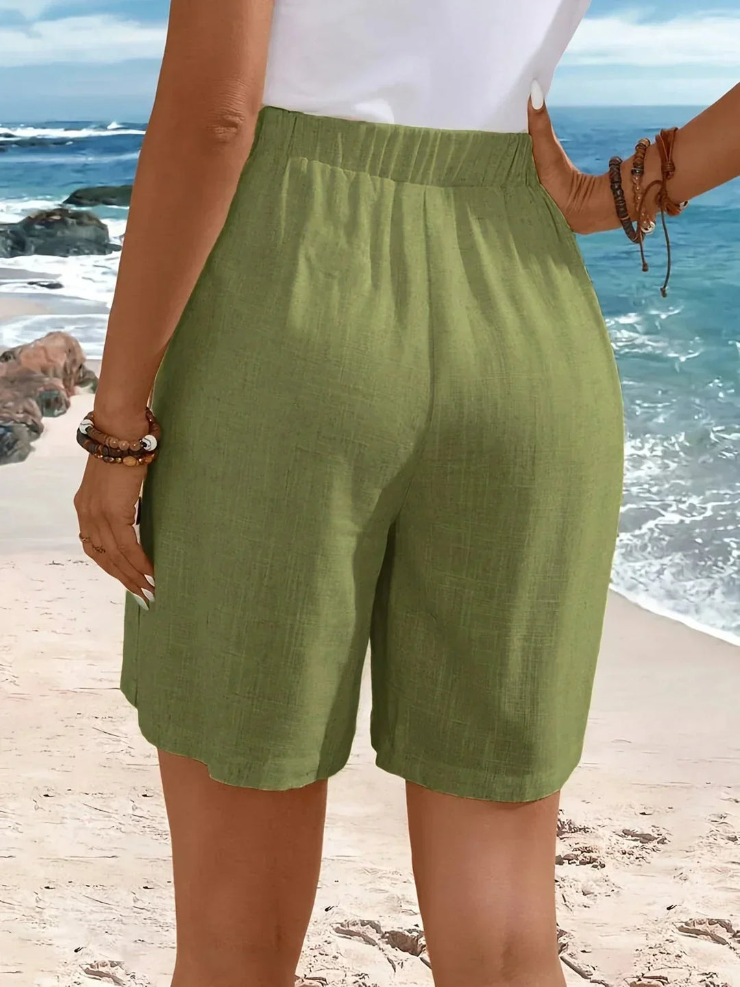 High-waisted detail of women's wide-leg shorts, featuring textured fabric and elegant side button accents.