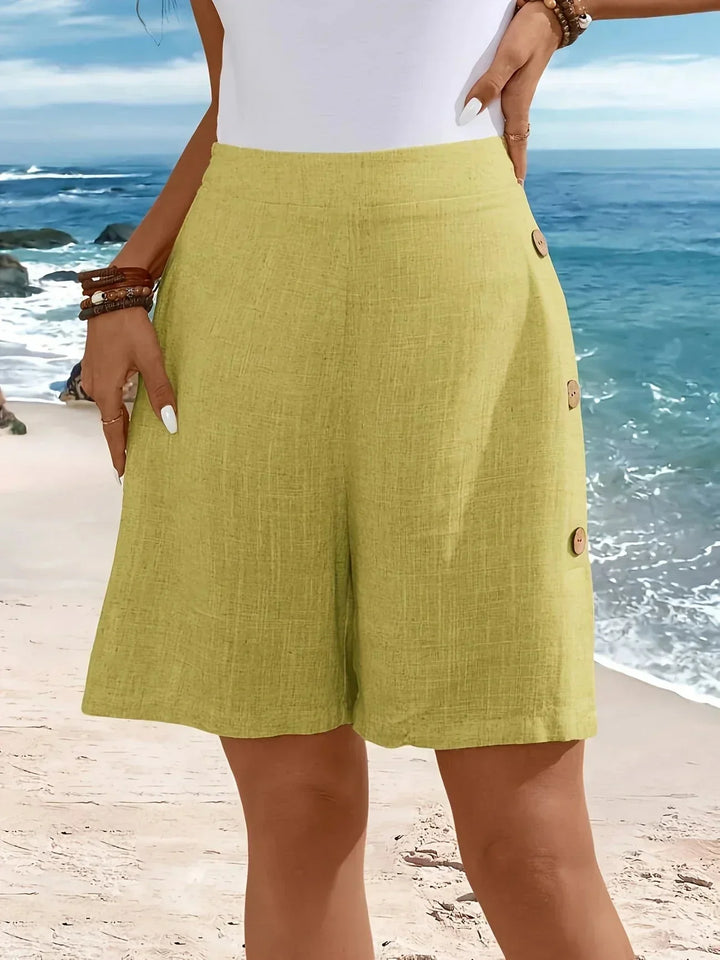 Front view: Women's textured high-waisted wide-leg pull-on shorts with stylish side buttons. Summer fashion.