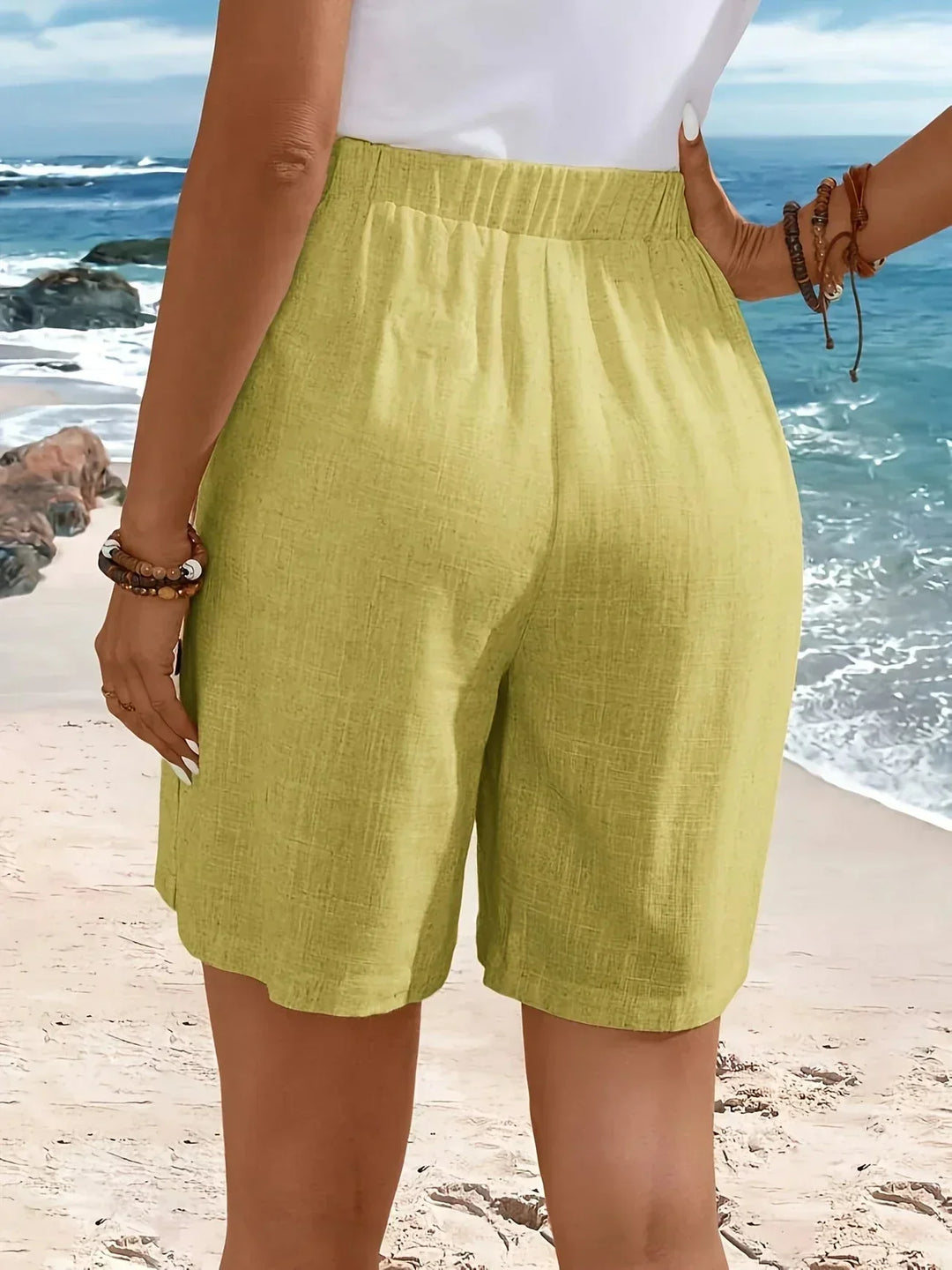Side profile: Comfortable women's wide-leg shorts, high-waisted with decorative side button detail. Casual wear.