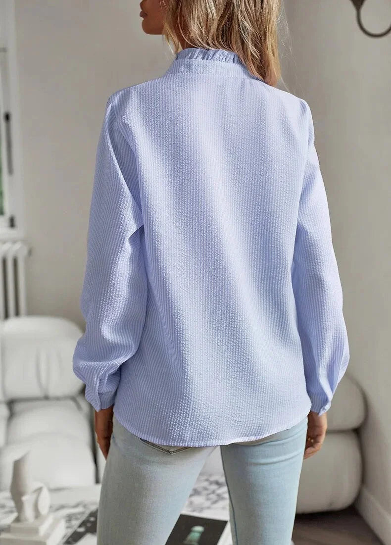 Feminine women's striped blouse, textured fabric, with a stylish ruffled collar and long sleeves.