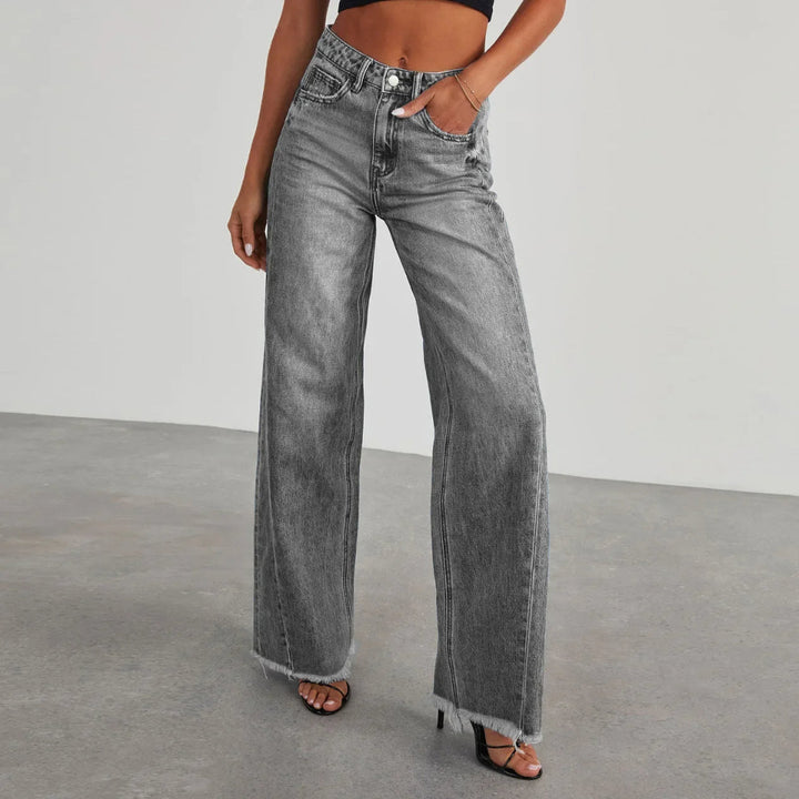 Mid-rise loose-fit women's wide-leg jeans, showcasing a unique frayed hem for a modern, trendy look.