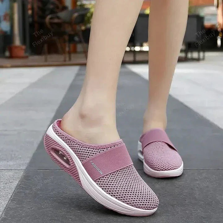 Hand holding a single lightweight women's air-cushion slip-on walking shoe, emphasizing its airy design.