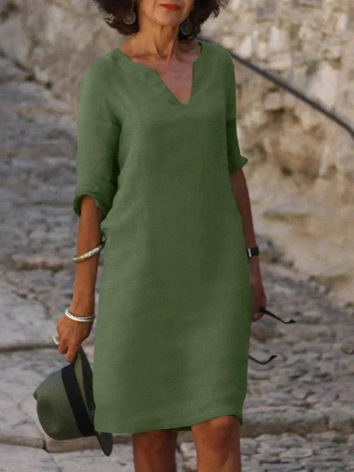 Elegant V-neck midi dress for women, featuring 3/4 sleeves, a relaxed fit, and practical side pockets.
