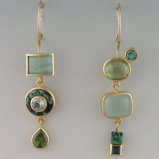 Women's vintage gold-tone asymmetric dangle earrings with striking green emerald gems for a fashion statement.