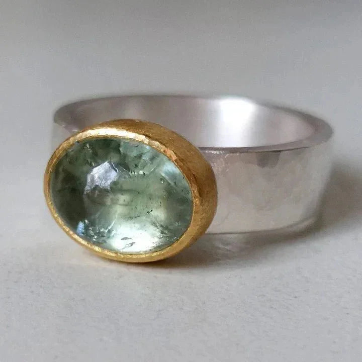 Women's vintage hammered silver ring featuring a vibrant green stone in a chic gold bezel setting. Perfect statement jewelry.