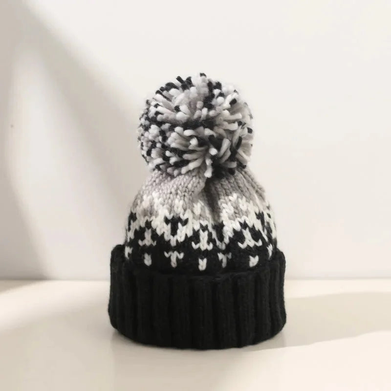 Women's white snowflake pom-pom beanie with ribbed cuff, ideal for festive winter cold weather style and warmth.