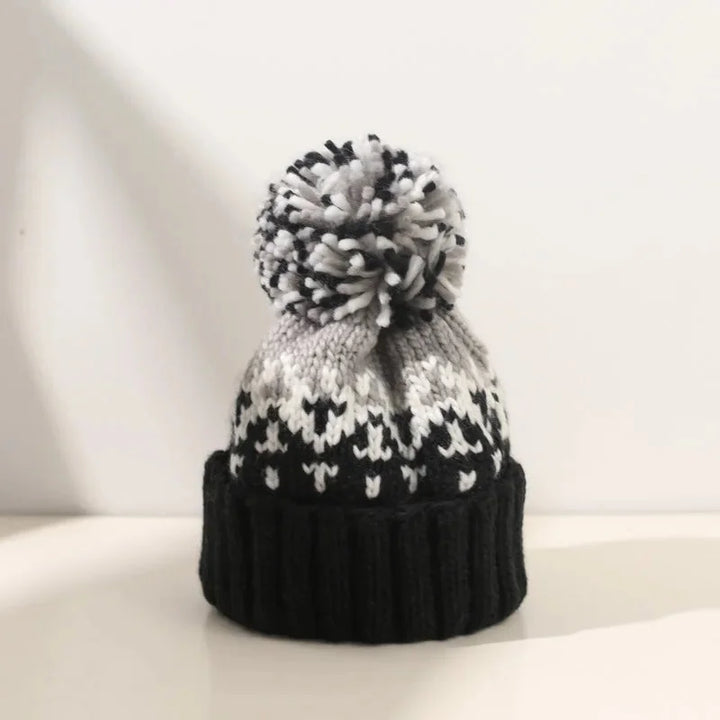 Women's white snowflake pom-pom beanie with ribbed cuff, ideal for festive winter cold weather style and warmth.