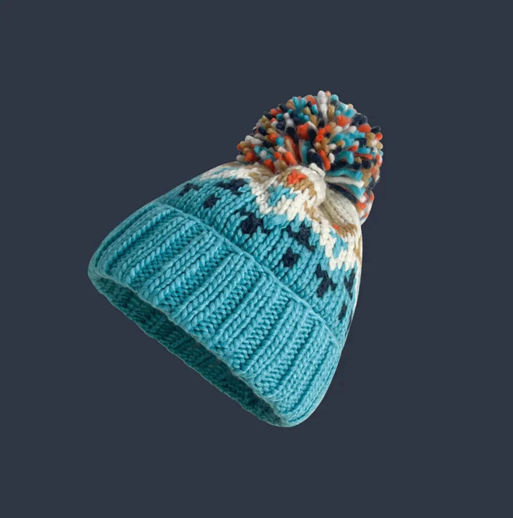 Festive women's snowflake pom-pom beanie, a stylish winter accessory for cold weather, featuring a ribbed cuff.