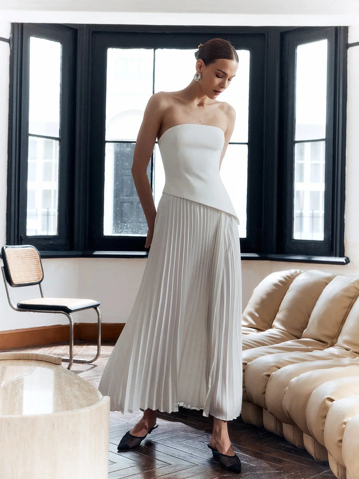 Flowing white strapless evening dress with pleats, an asymmetric hem, ideal for formal events.