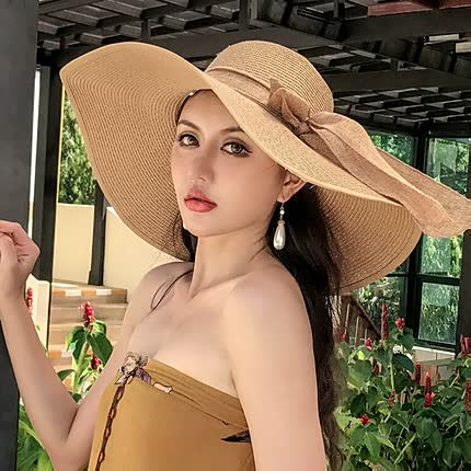 Women's wide brim straw sun hat with elegant bow, perfect for beach style & summer fashion.
