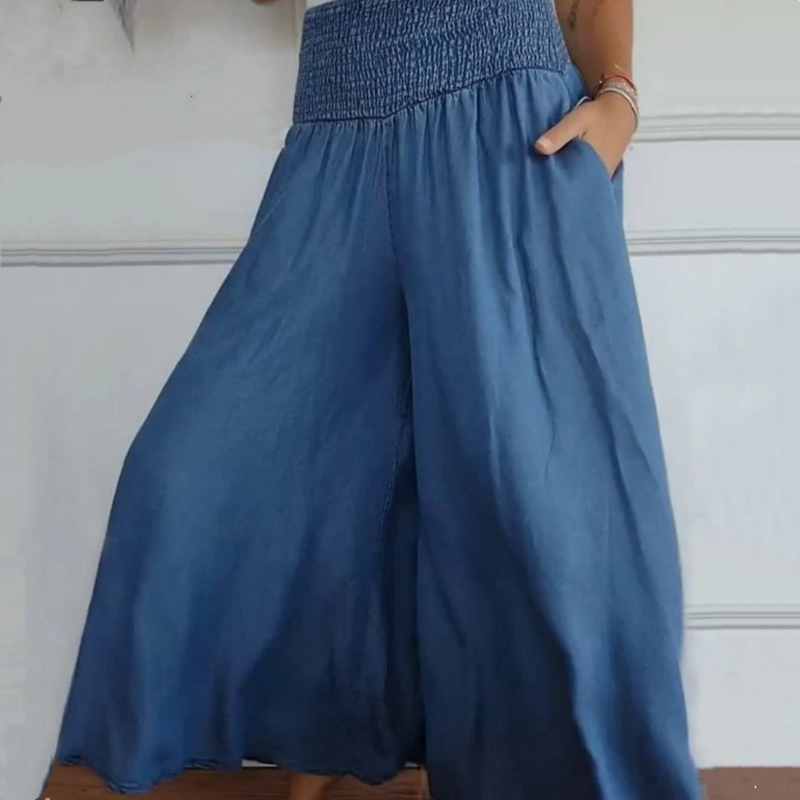 Close-up of the smocked high-waist and wide-leg cut on women's stylish denim trousers.
