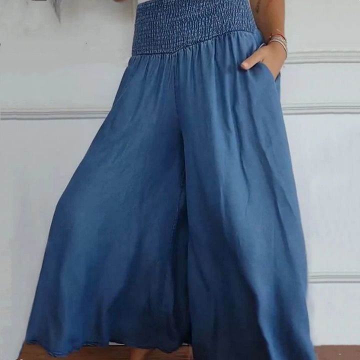 Close-up of the smocked high-waist and wide-leg cut on women's stylish denim trousers.